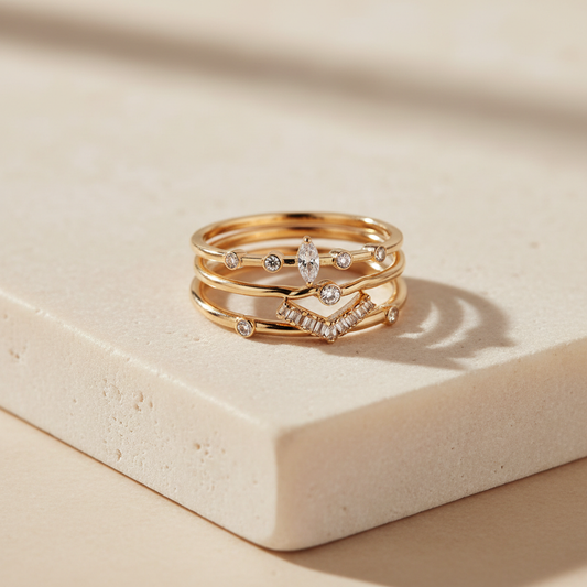 Three gold-tone stacking rings with clear crystal accents on cream stone