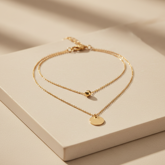 Delicate gold-tone layered necklace with round pendant on cream stone